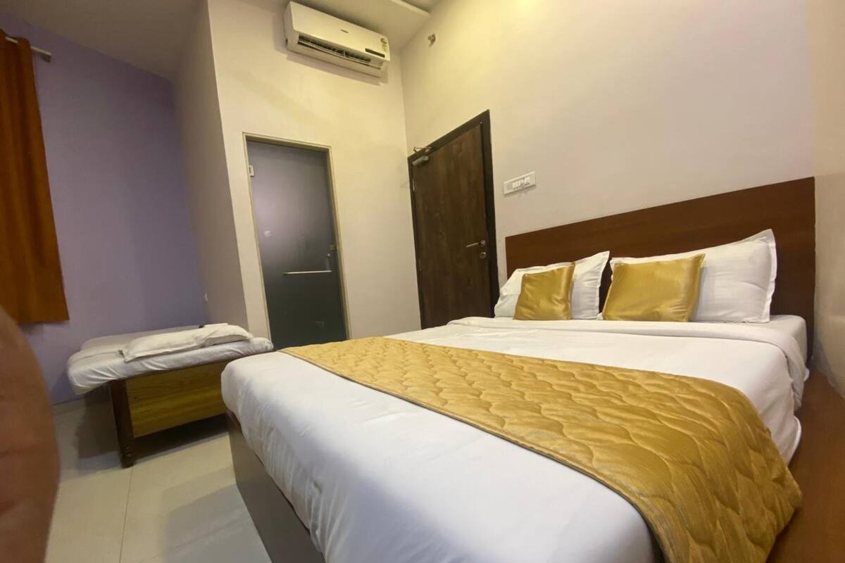 Una habitación de hotel con una cama grande, una mesita de noche, un armario y un equipo de aire acondicionado en la pared.