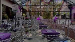 A long table set with crystal glassware and silverware, under a glass roof with decorative elements. - Karen Blixen Coffee Garden & Cottages (Nairobi)