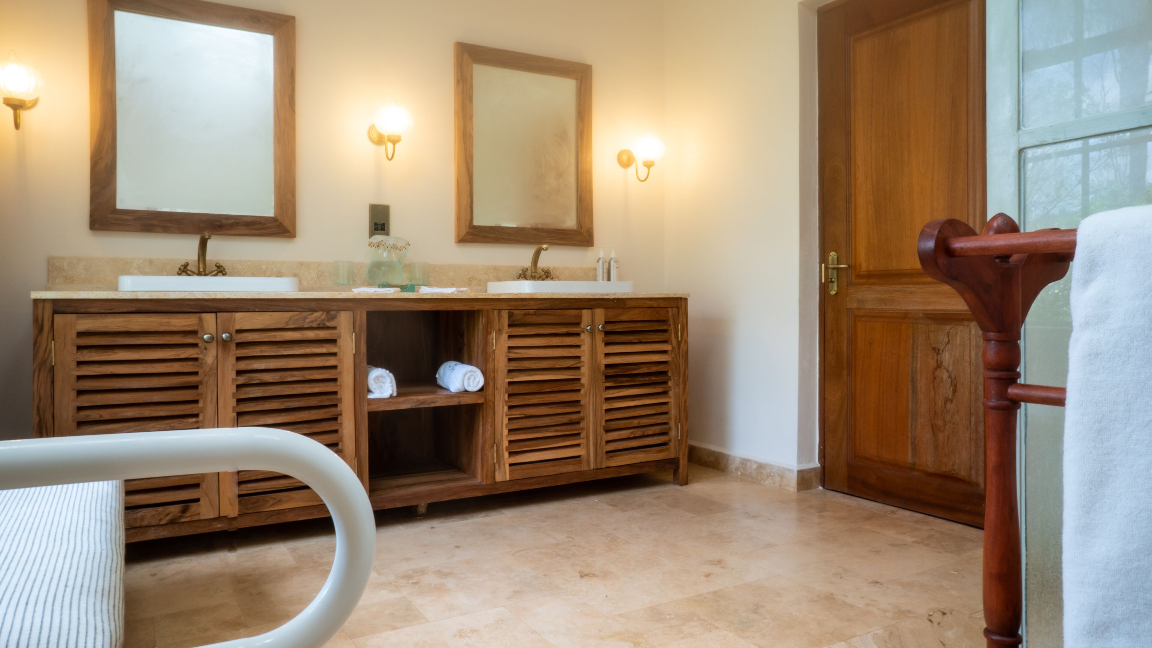 A bathroom with wooden cabinets, two sinks, and wall-mounted lights.