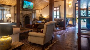 A cozy living room with a fireplace, comfortable seating, and a television mounted on the wall. - Karen Blixen Coffee Garden & Cottages (Nairobi)