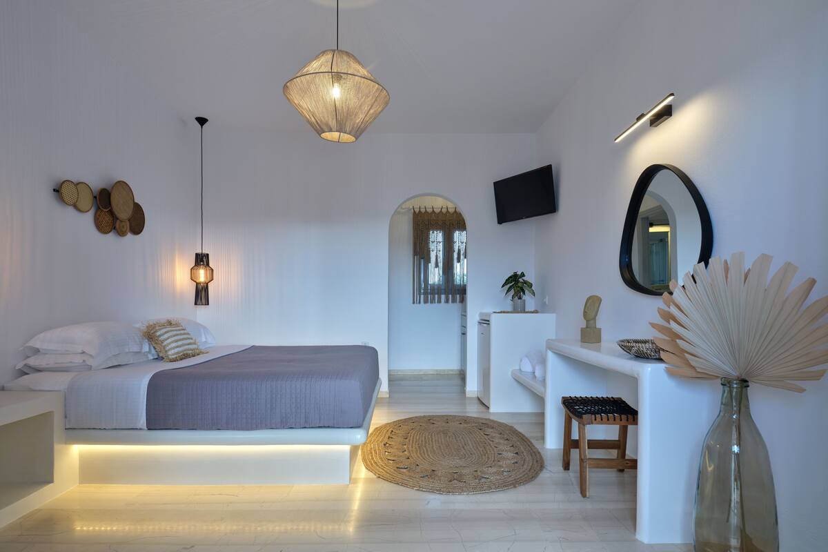 A modern bedroom with a bed, bedside table, and a desk with a chair.