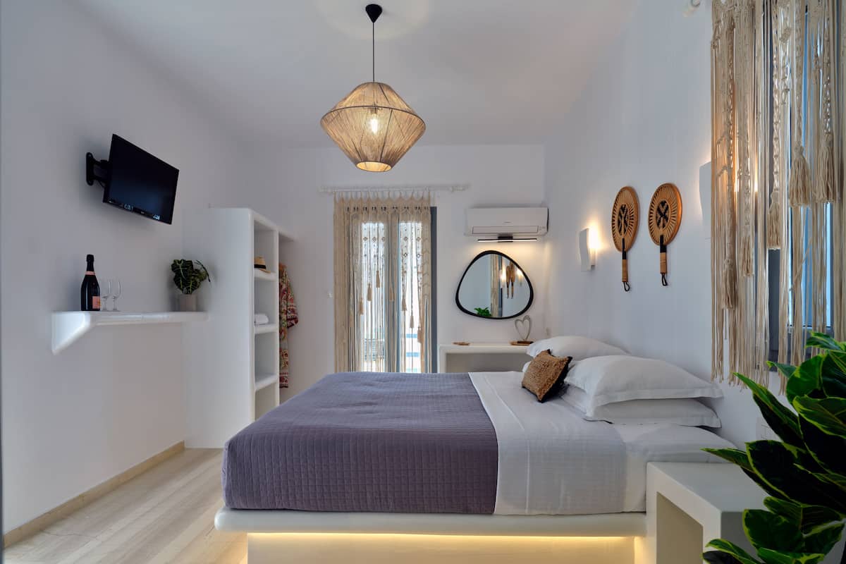 A modern bedroom with a bed, bedside tables, a mounted TV, and a unique hanging light fixture.