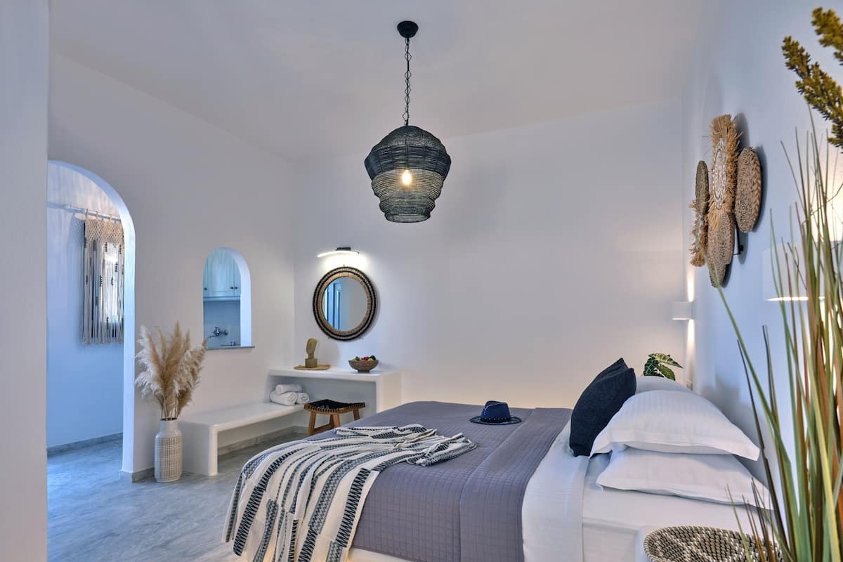 A modern bedroom with a bed, bedside table, and a hanging light fixture.