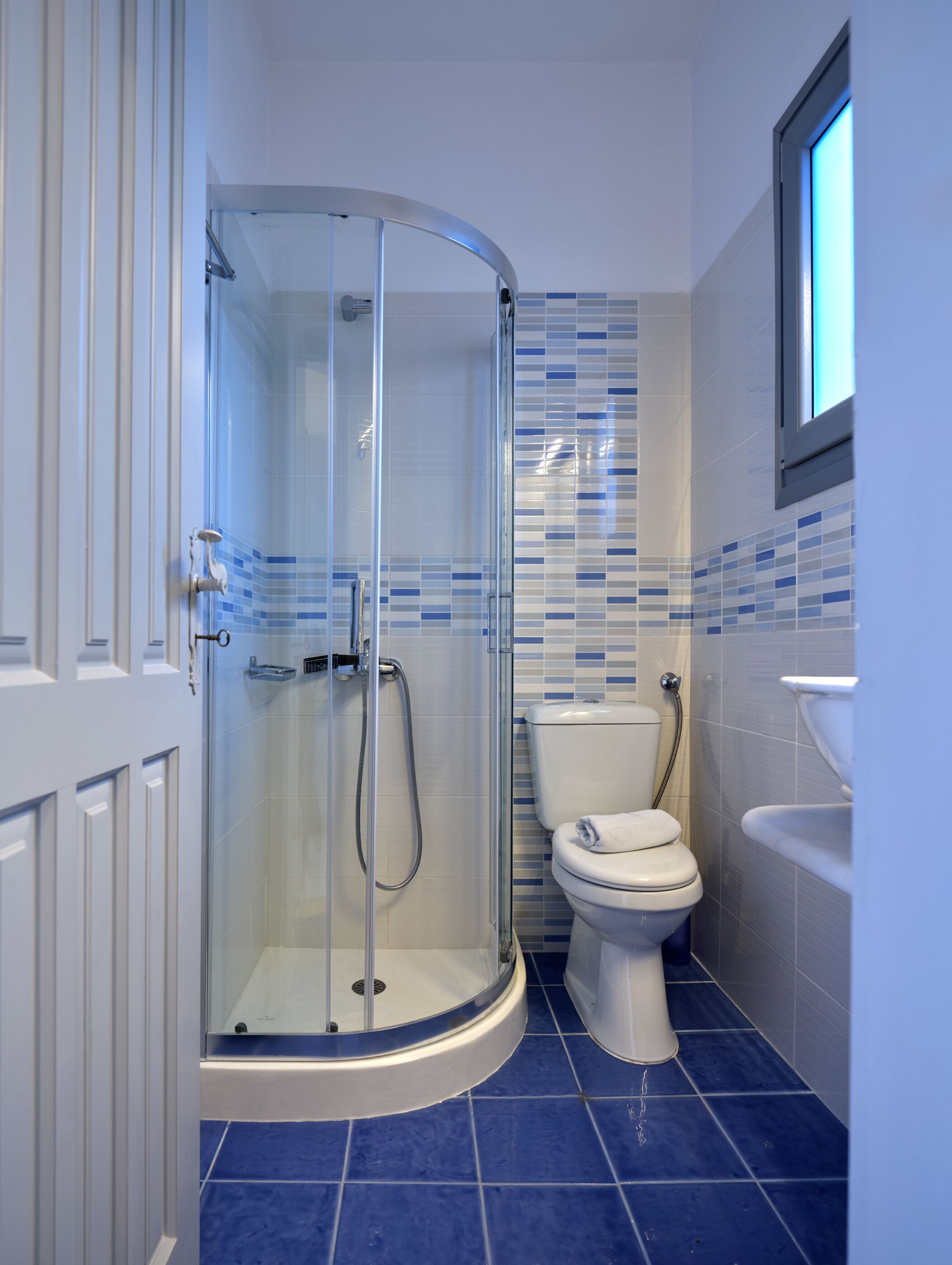 Un baño con ducha de vidrio, inodoro y lavabo.