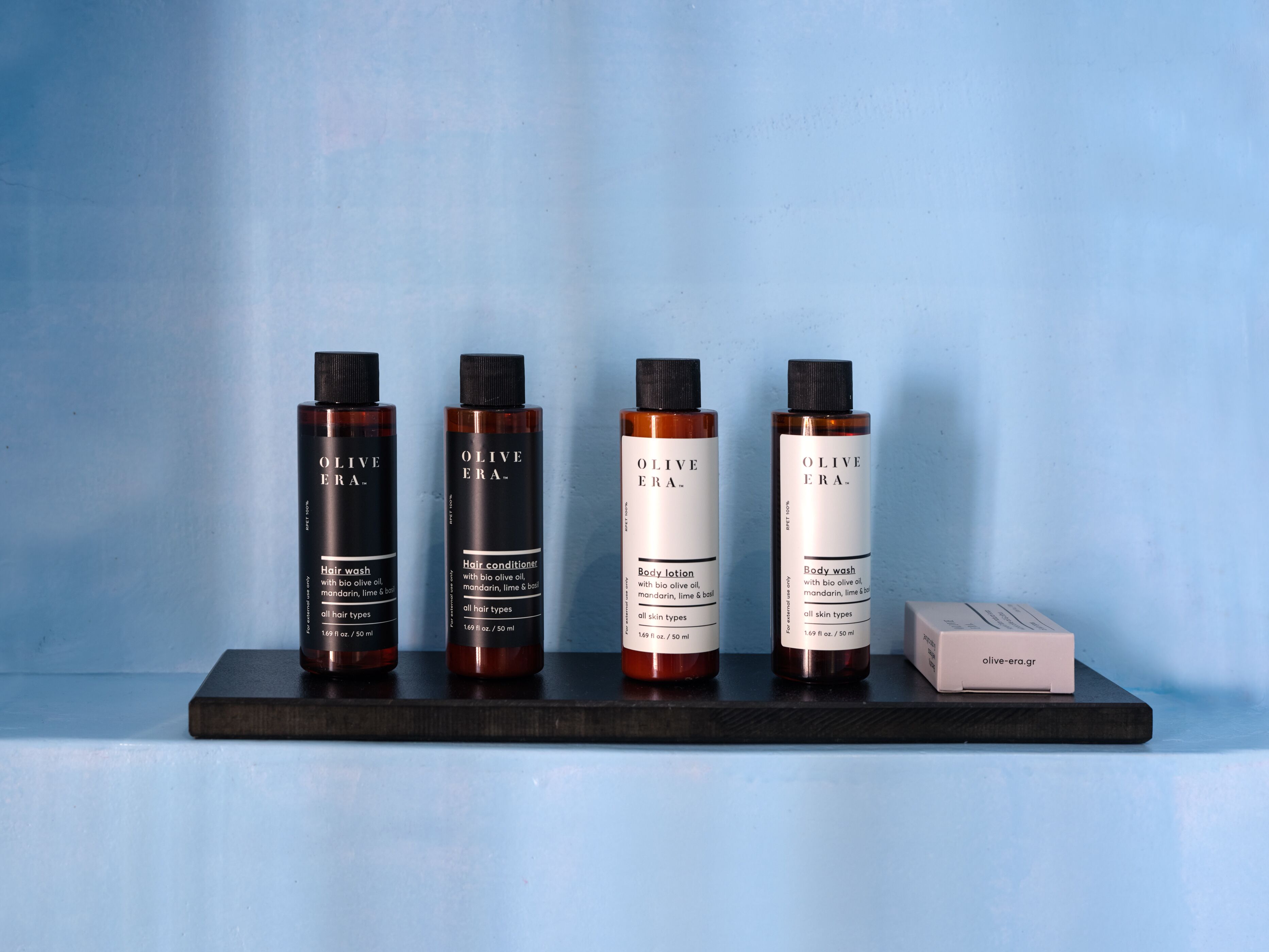 Four bottles of Olive Era hair care products on a shelf.