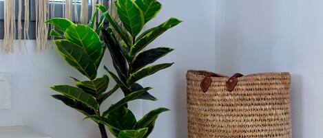 A room with a potted plant, a woven basket, and a macrame wall hanging.