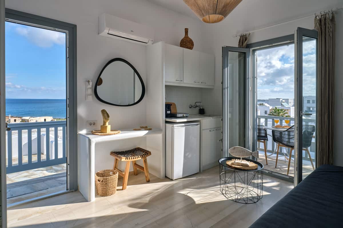 A modern apartment with a balcony, a kitchenette, and a dining area with a view of the sea.