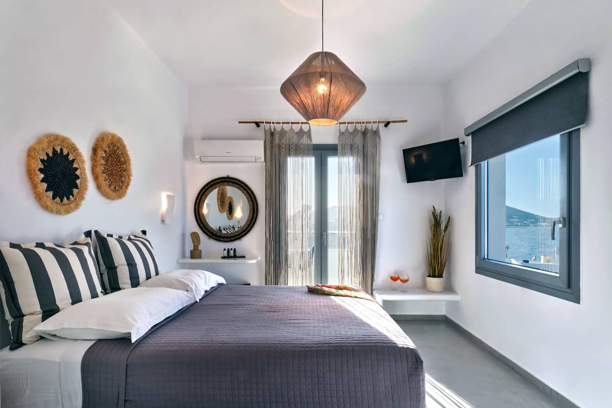 A modern bedroom with a large bed, a television, a window with a view, and decorative wall art.