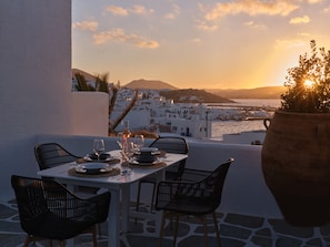 A table set for two with a view of a coastal town at sunset. - Ariti Seaside Residence (Paros)