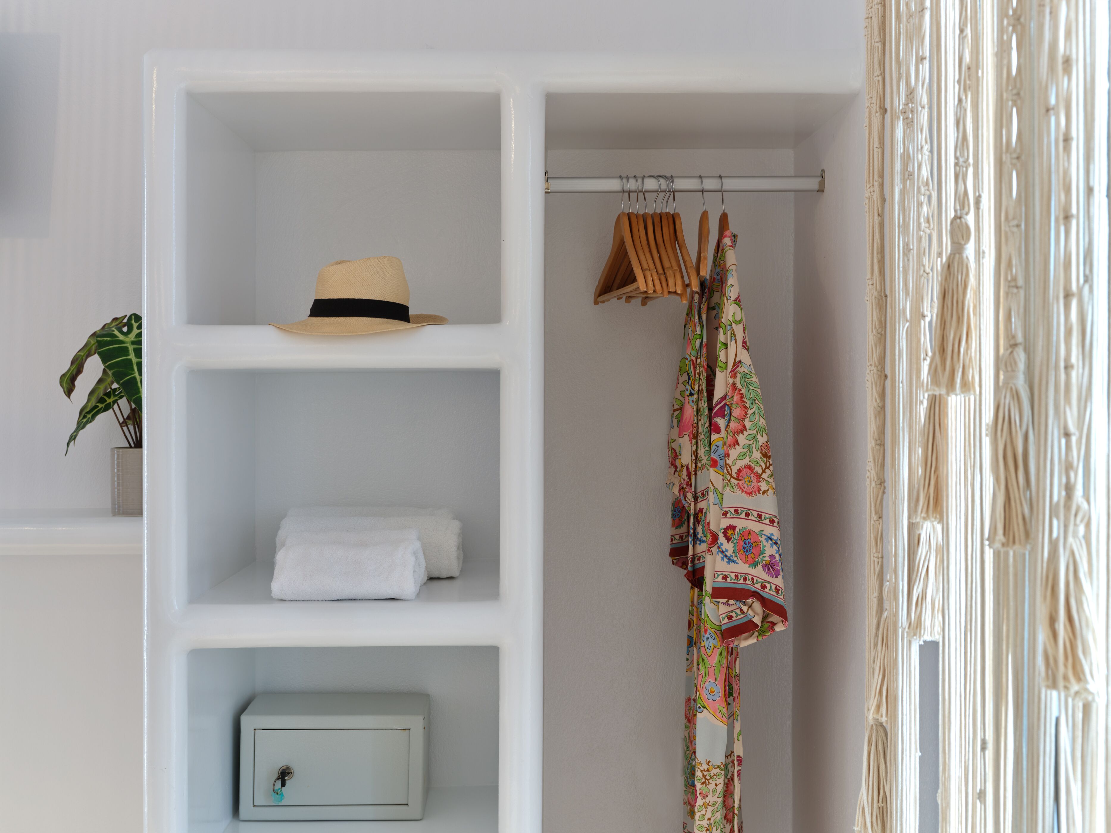 A white wardrobe with a hat, folded towels, and a small box.