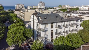 A hotel with multiple balconies, a parking area, and a view of the sea. - Hotel Luana  (Riccione)