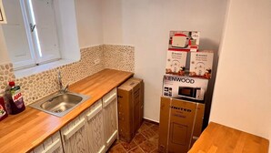 Una cocina con encimera de madera, un lavamanos y un salpicadero con diseño. Hay cajas apiladas contra la pared, y se ve una lámpara en el techo.
