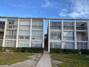 A multi-story building with large windows, a central entrance, and a pathway leading to the entrance.