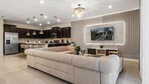 A modern kitchen with dark cabinets, a large island, and pendant lighting.