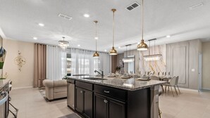 A spacious kitchen with a central island, pendant lighting, and a dining area with chairs.