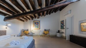 Un dormitorio con cama, dos sillas, un escritorio y obras de arte en las paredes.