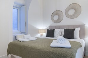 Un lit bien fait, avec une couverture verte, des oreillers blancs et une serviette pliée posée sur le côté.