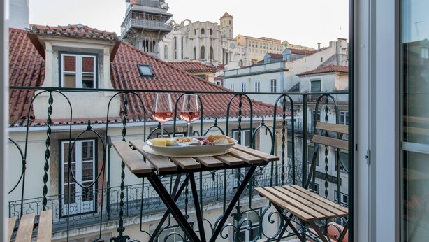 Un balcó amb taula per a dues persones, amb vista a una ciutat i edificis històrics.