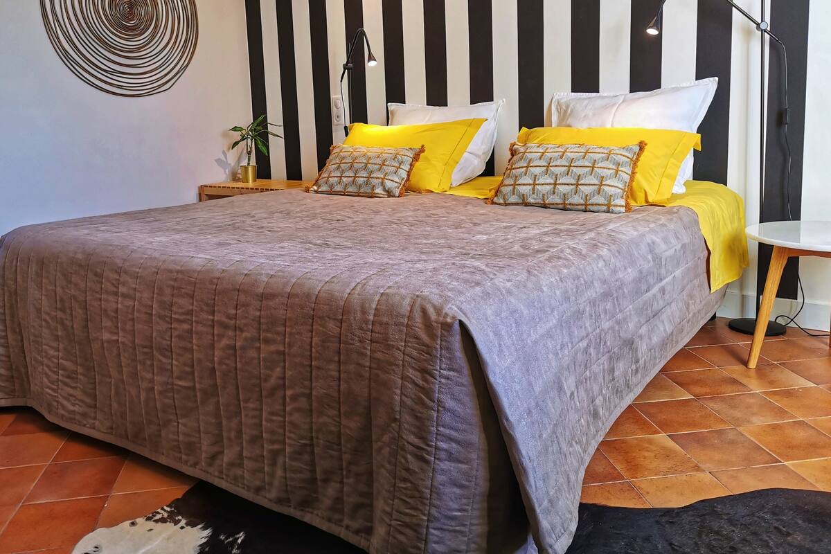 Un dormitorio con una cama, dos mesitas de noche, una lámpara y una obra de arte en la pared.