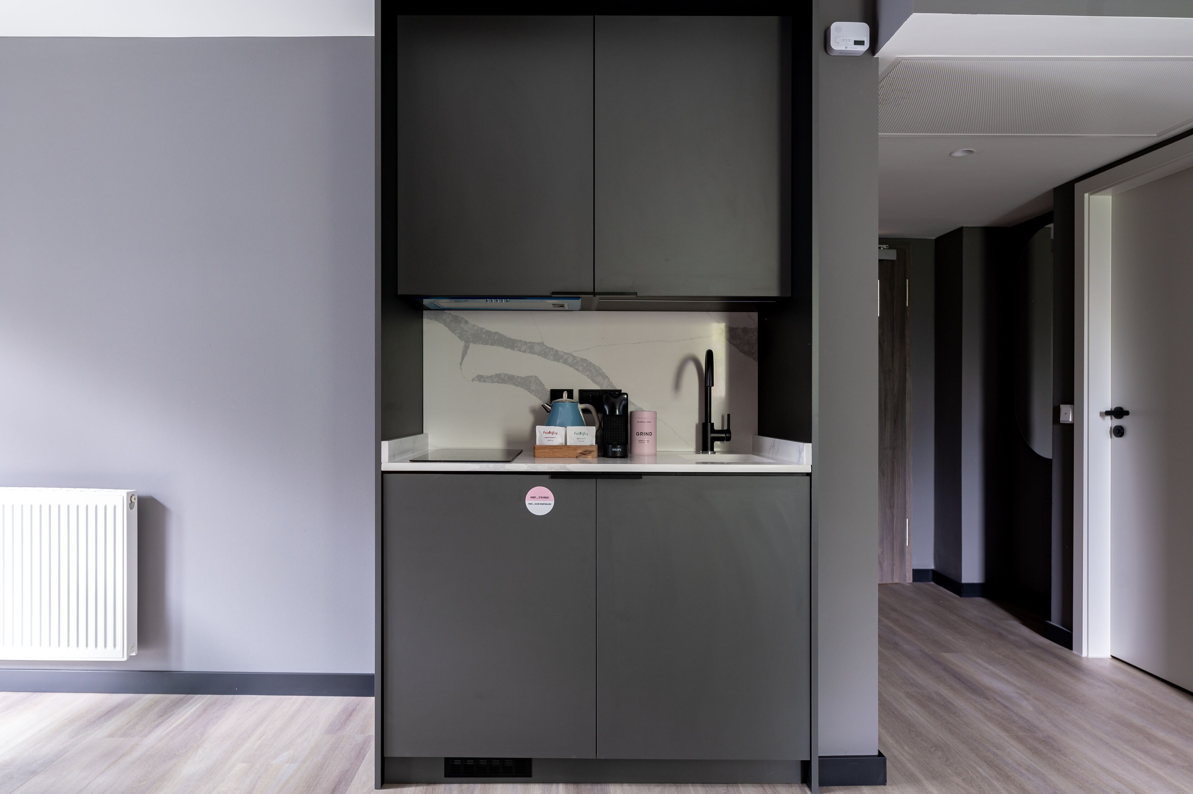 A compact kitchen with a built-in microwave, a coffee maker, and a kettle on the countertop.