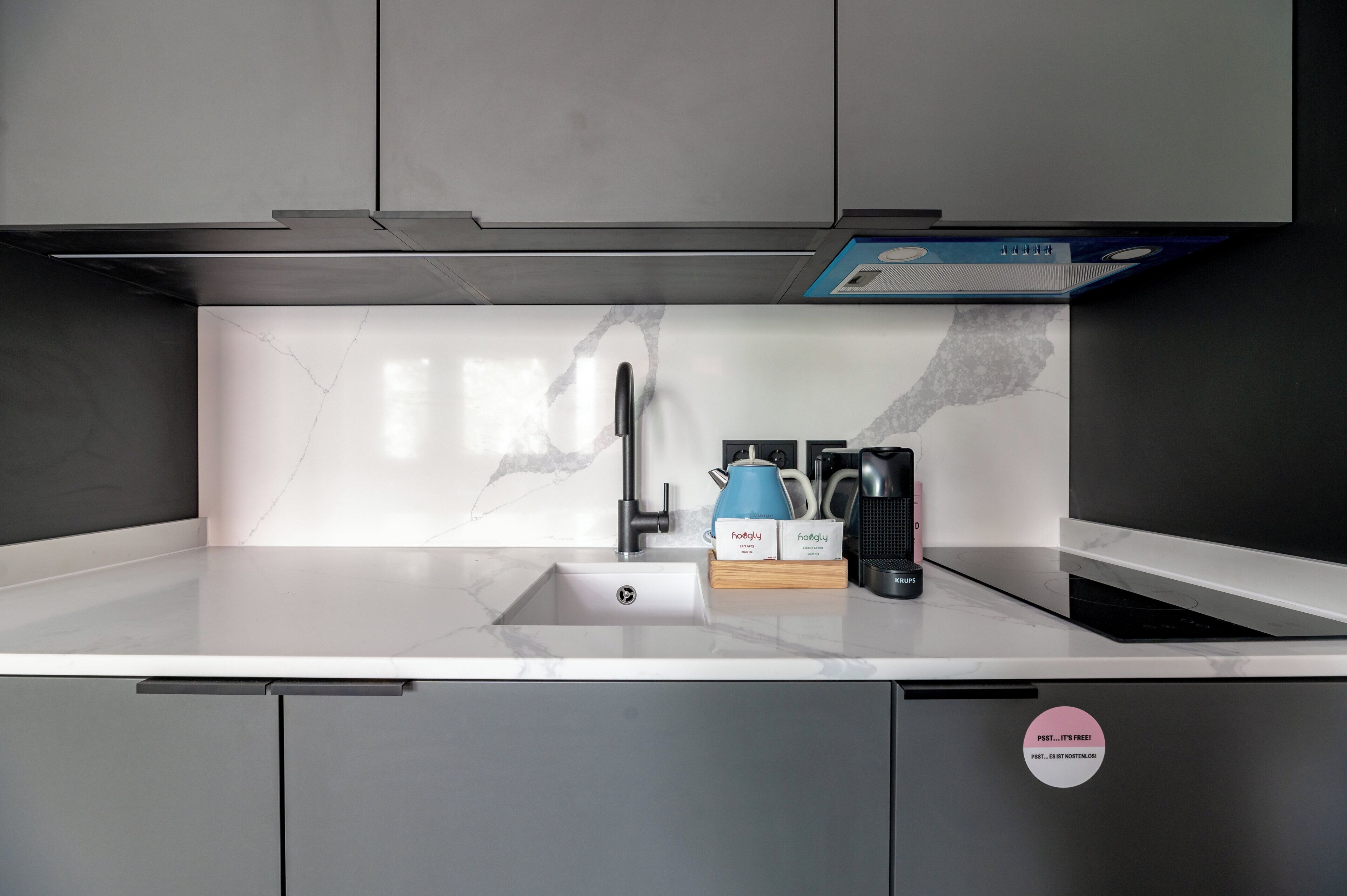 A modern kitchen with a built-in sink, a coffee maker, and a kettle on the countertop.