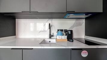 A modern kitchen with a built-in sink, a coffee maker, and a kettle on the countertop.