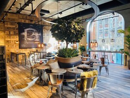 Un caffè moderno con pareti in legno, tavoli rotondi e piante sospese.