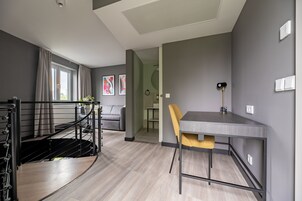 Un soggiorno moderno con una scala, una zona pranzo con tavolo e sedia, e vista all'esterno attraverso una finestra.