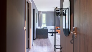 A modern hotel room with a grey sofa, a small round table, and a large mirror.