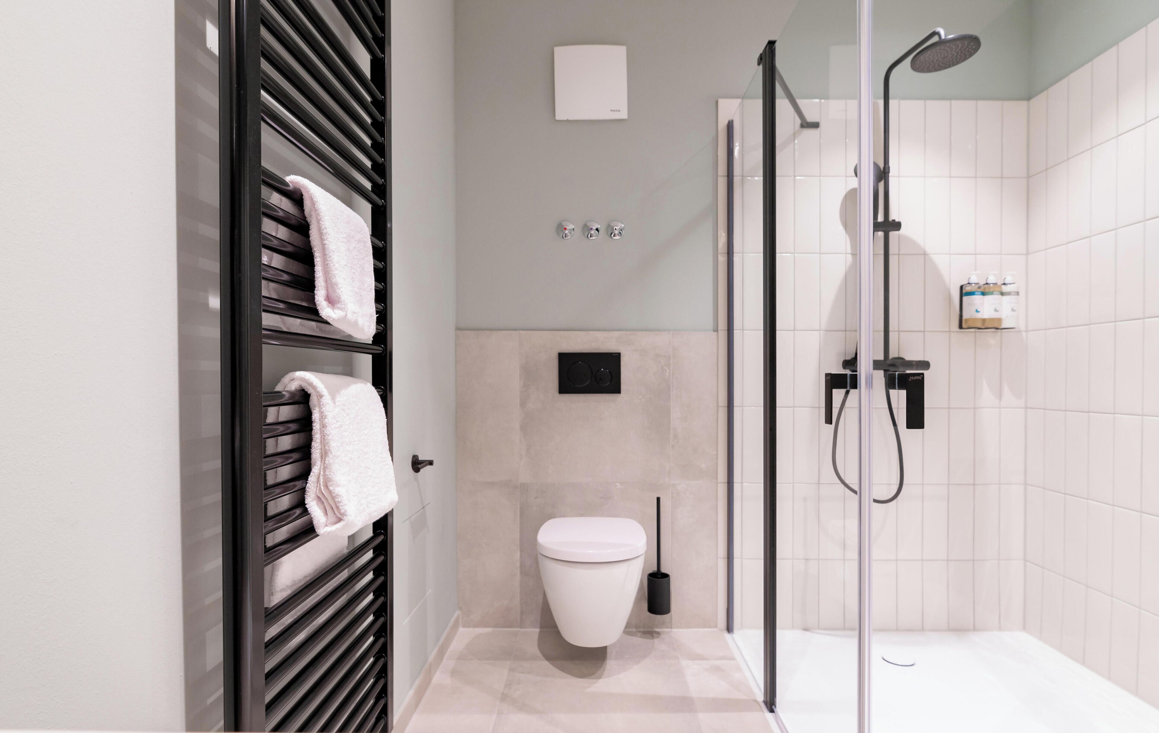 Studio | Badkamer | Een douche, designer toiletartikelen, een haardroger, handdoeken