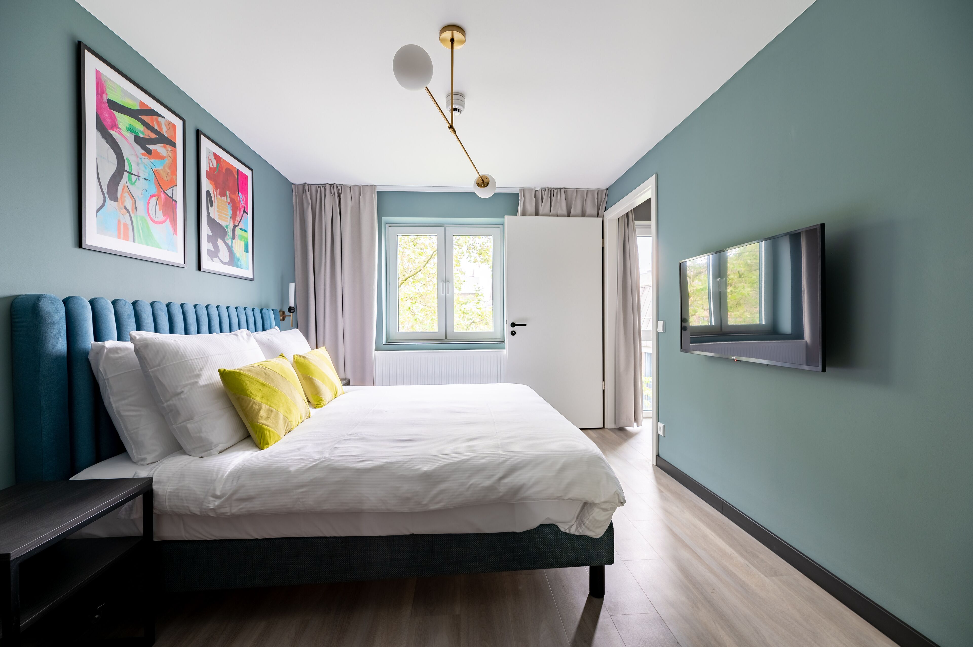 Un dormitorio moderno con una cama, un televisor y obras de arte en la pared.