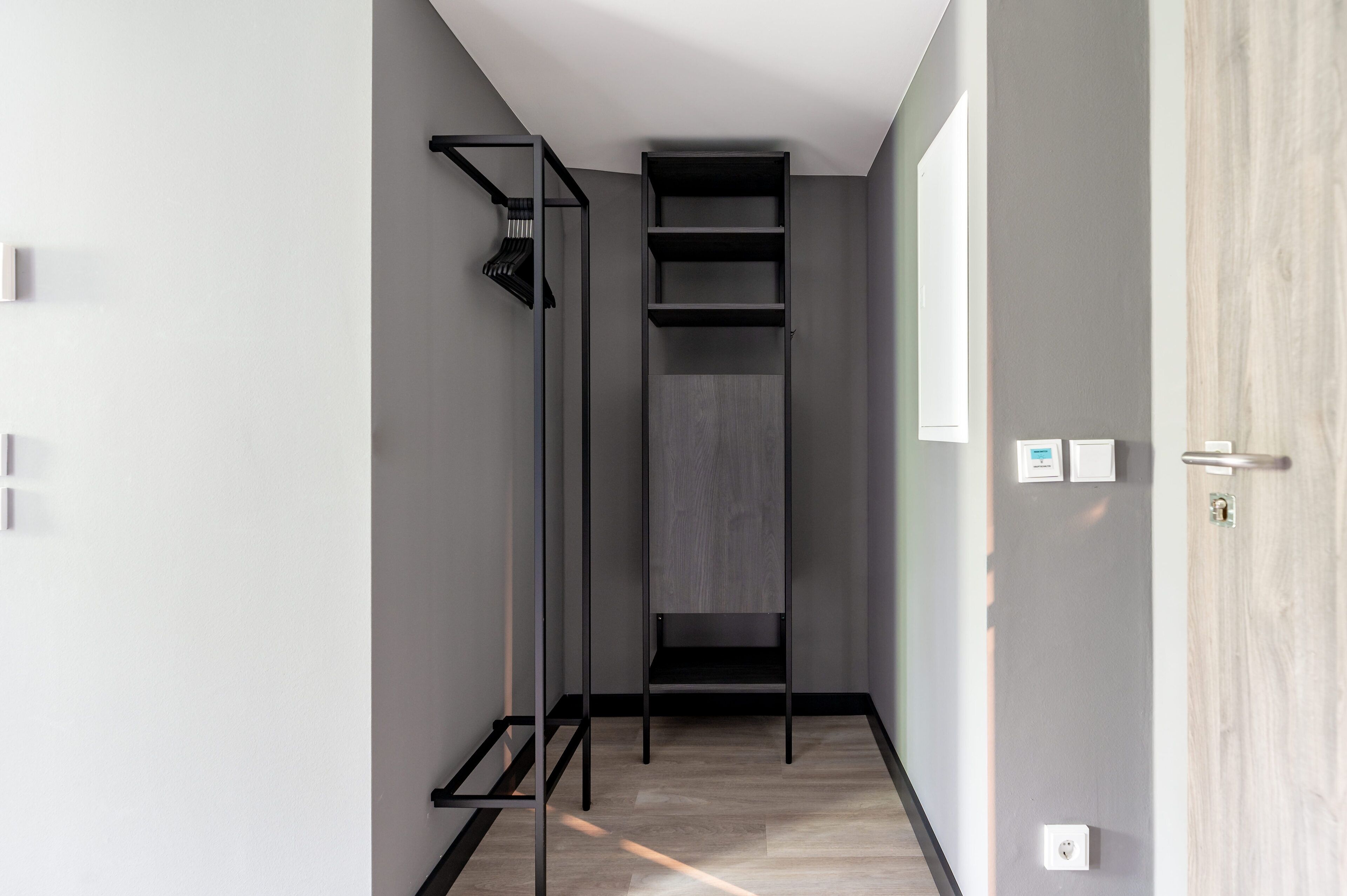 Un pasillo estrecho con una estantería empotrada, una puerta de cristal y una puerta de madera.