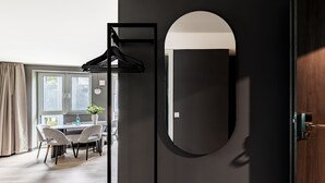 A modern room with a large mirror, a round mirror, and a black hanger on the wall.
