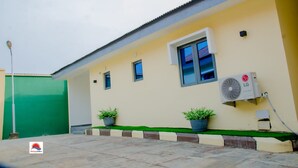 A building with a green gate, a yellow wall, and an air conditioning unit. - Horizon Suites (Ibadan)