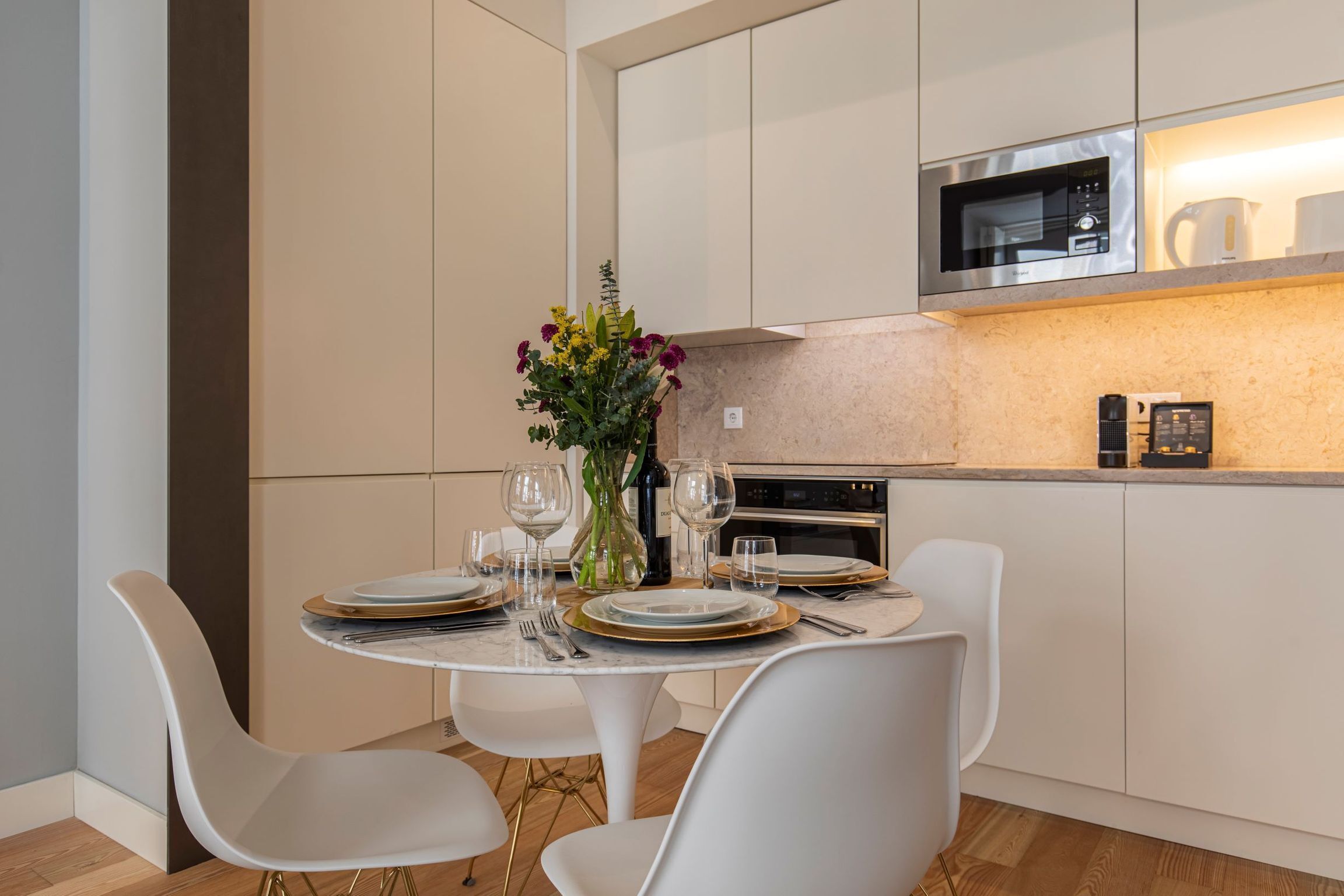 A modern kitchen with white cabinets, a built-in microwave, and a coffee maker.