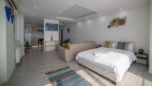 A modern bedroom with a large bed, a sofa, a small kitchen area, and a dining table. - Niagara Apartments (Baia Mare)