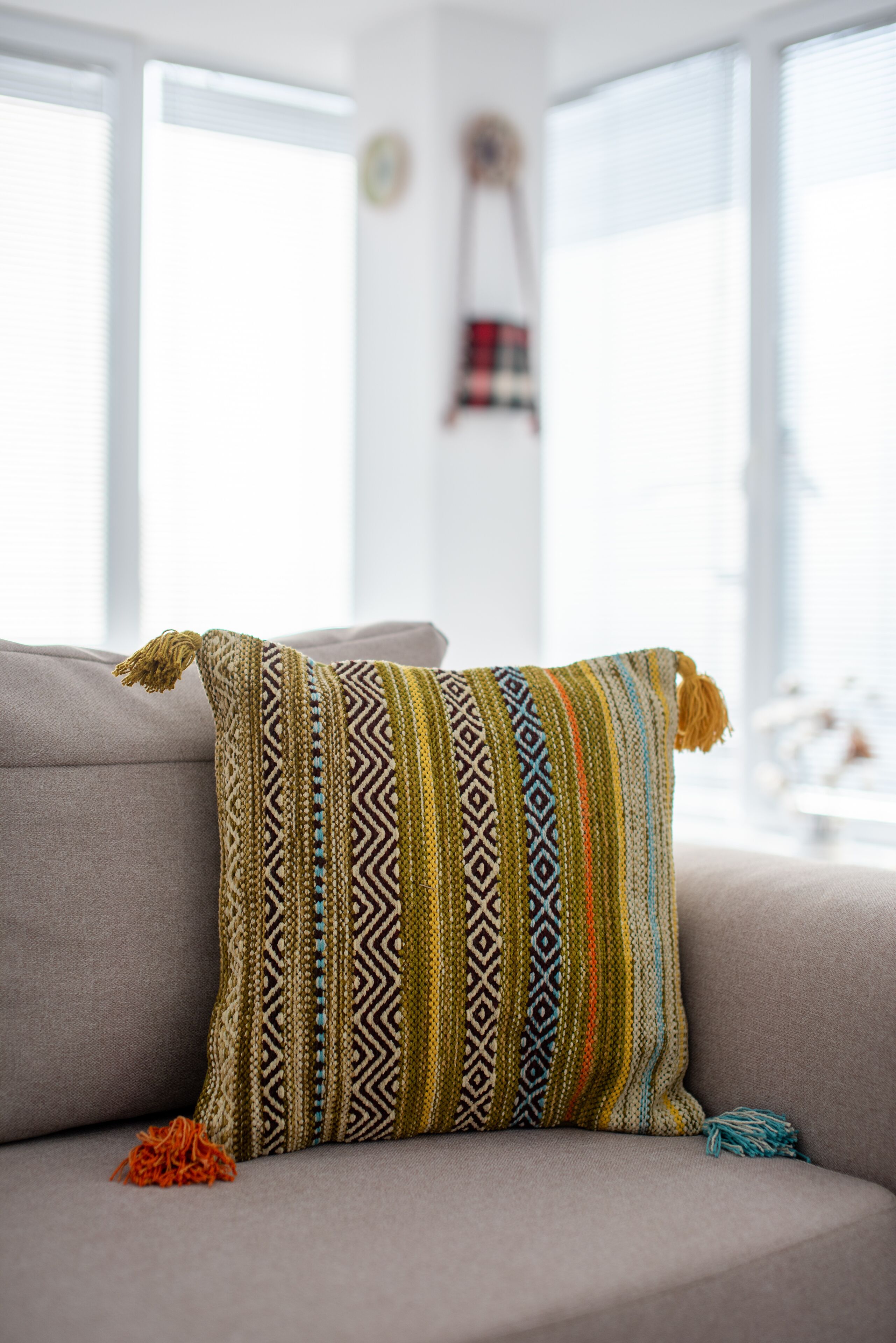 Un canapé agrémenté d’un coussin décoratif à motifs et de quelques glands.