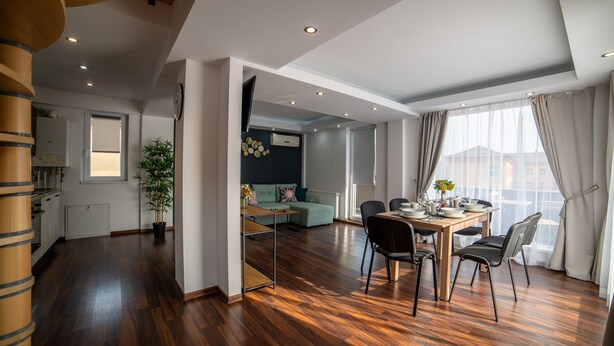 A modern kitchen with wooden cabinets and a dining area with a table and chairs. - Niagara Apartments (Baia Mare)