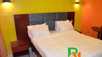 Una habitación de hotel con cama, mesitas de noche y dos lámparas fijadas a la pared.