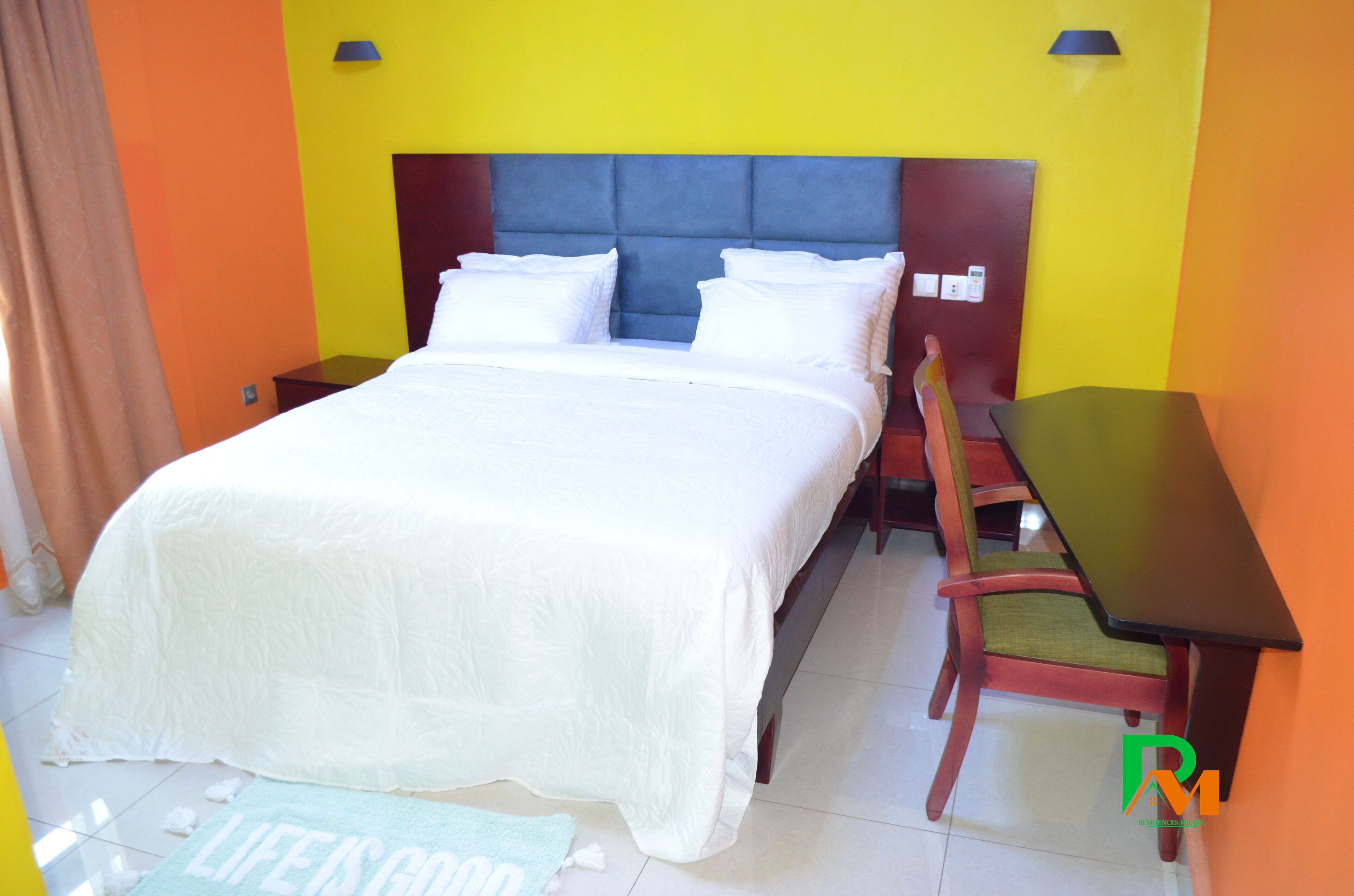 A hotel room with a bed, a nightstand, a desk, and a chair.
