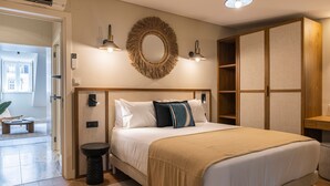 A modern bedroom with a large bed, bedside lamps, a round mirror, and a wardrobe.