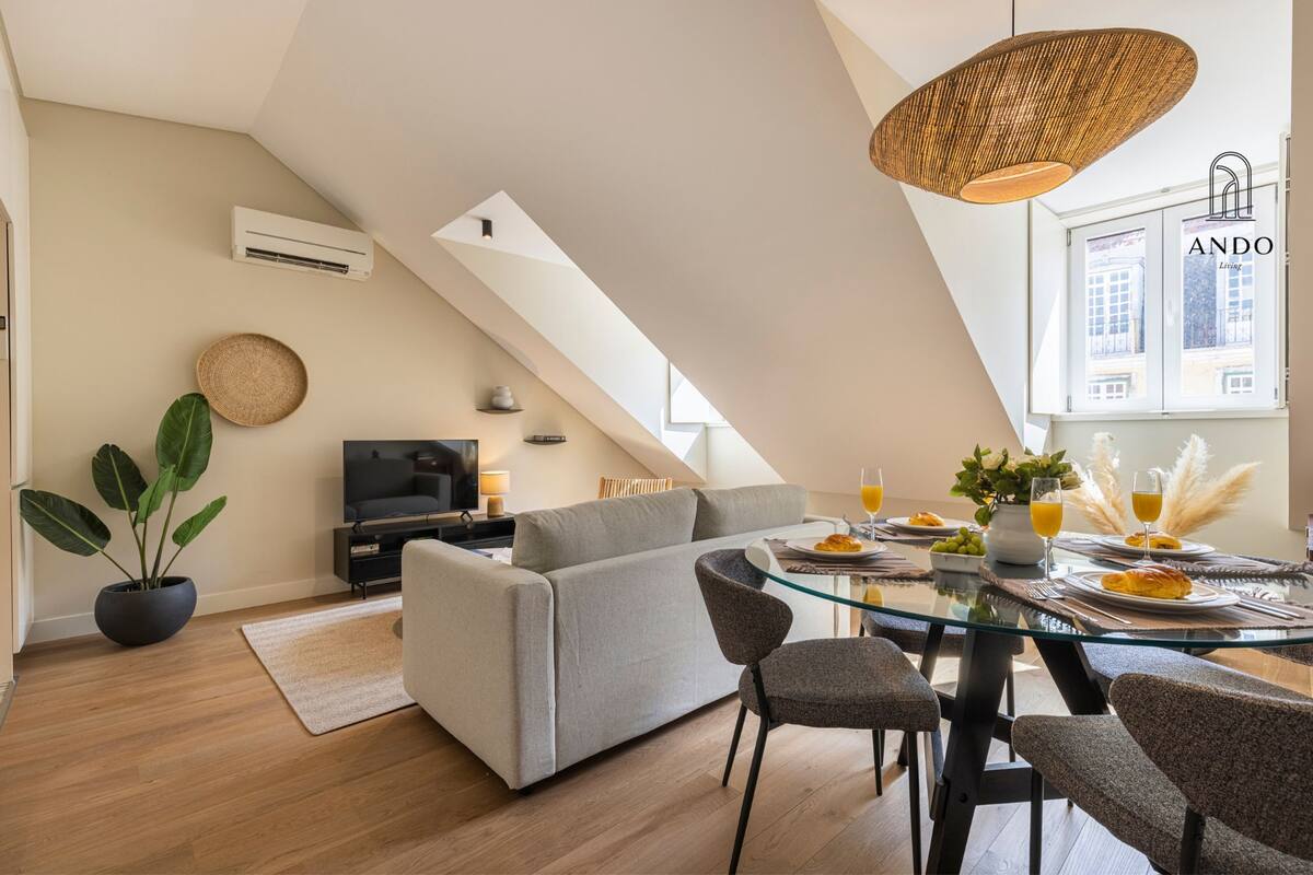 Un salon moderne avec un canapé, un téléviseur et un coin repas doté d’une table en verre.