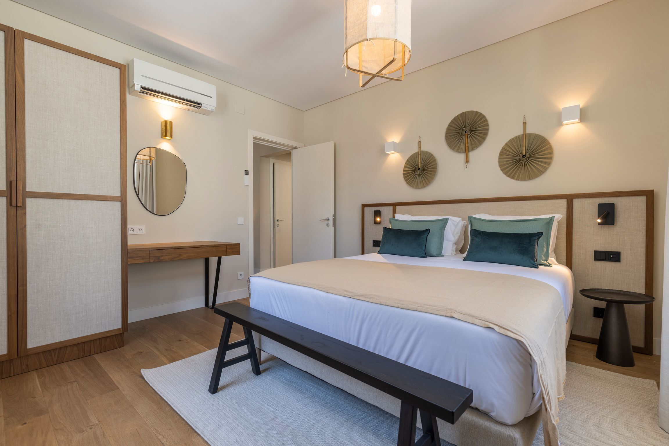 Une chambre à coucher moderne avec un grand lit, des tables de chevet, un banc et des appliques murales décoratives.