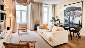 A modern living room with a sofa, a dining table, and a large window.