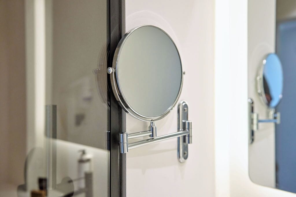 A bathroom with a round mirror mounted on a wall, a towel rack, and a toilet.