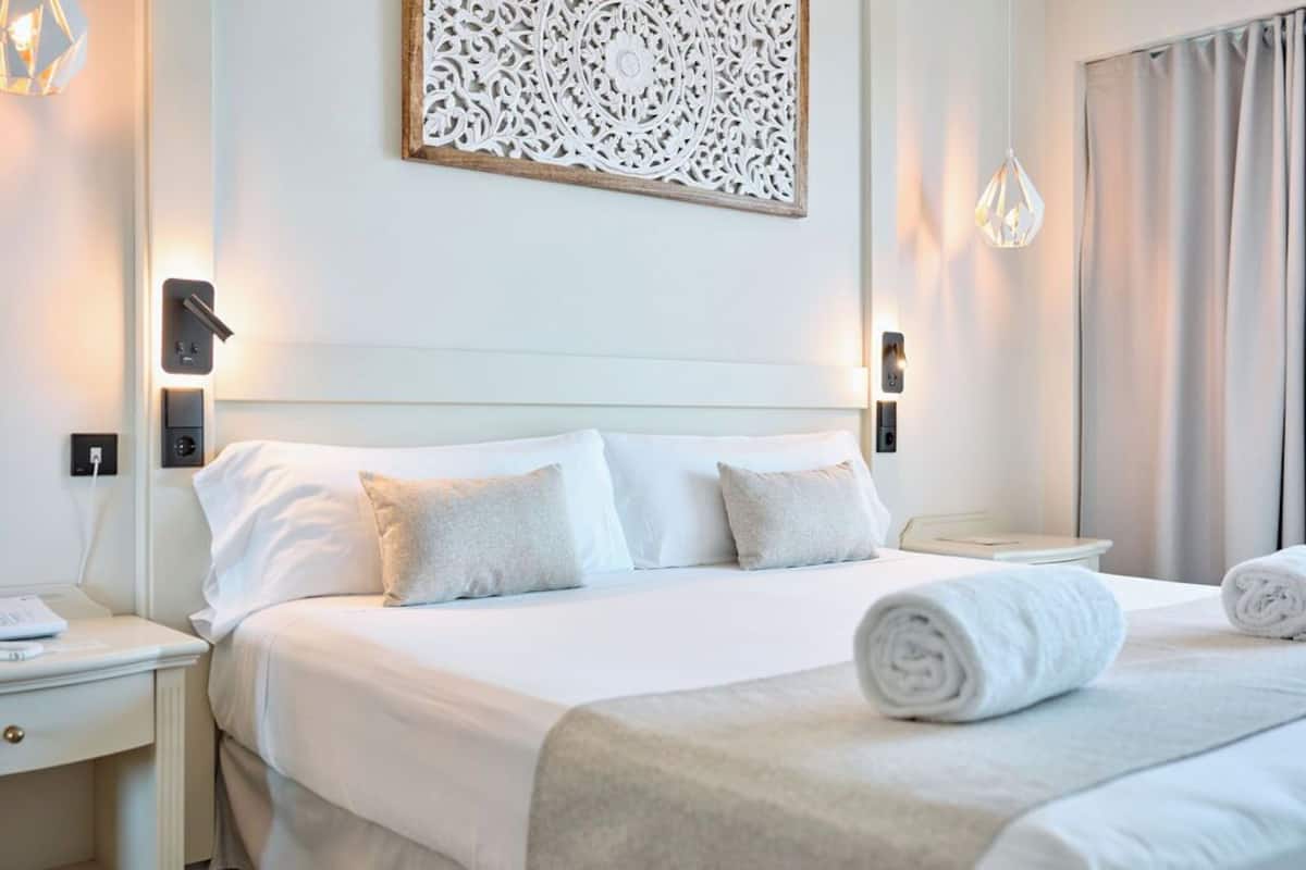 Ein ordentlich eingerichtetes Hotelzimmer mit einem großen Bett, zwei Nachttischen und einer dekorativen Wandgestalt.