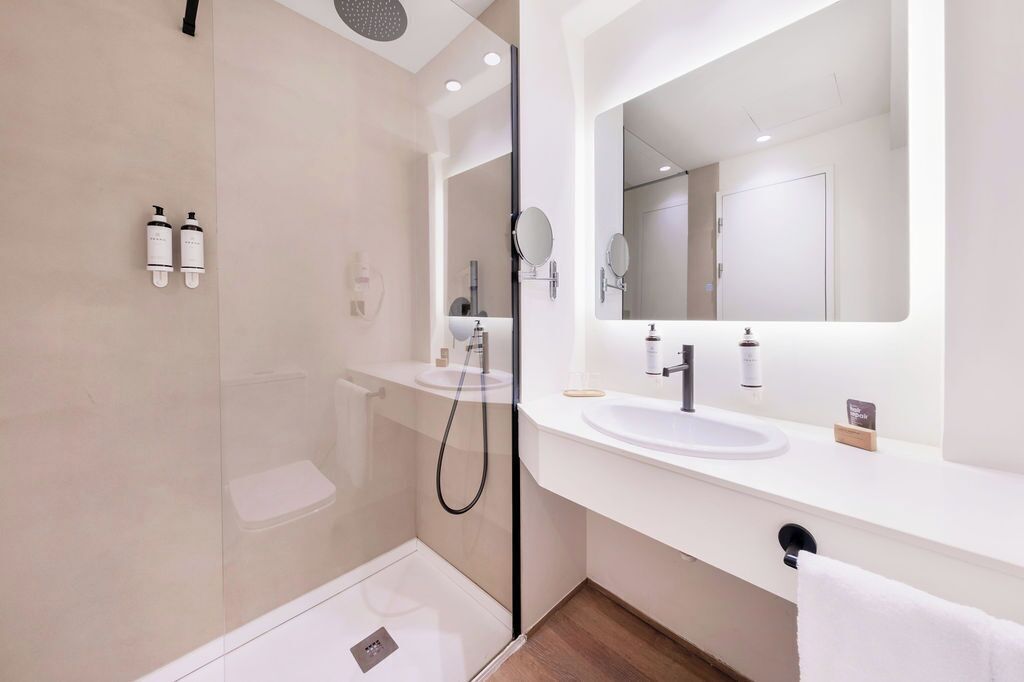 A modern bathroom with a glass-enclosed shower, a white sink, and a large mirror.