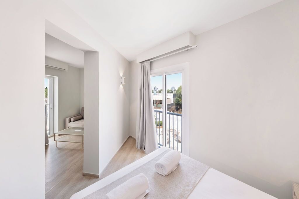 A modern hotel room with a balcony, a sofa, and a view of the outside.
