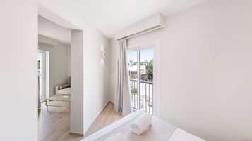 A modern hotel room with a balcony, a sofa, and a view of the outside.