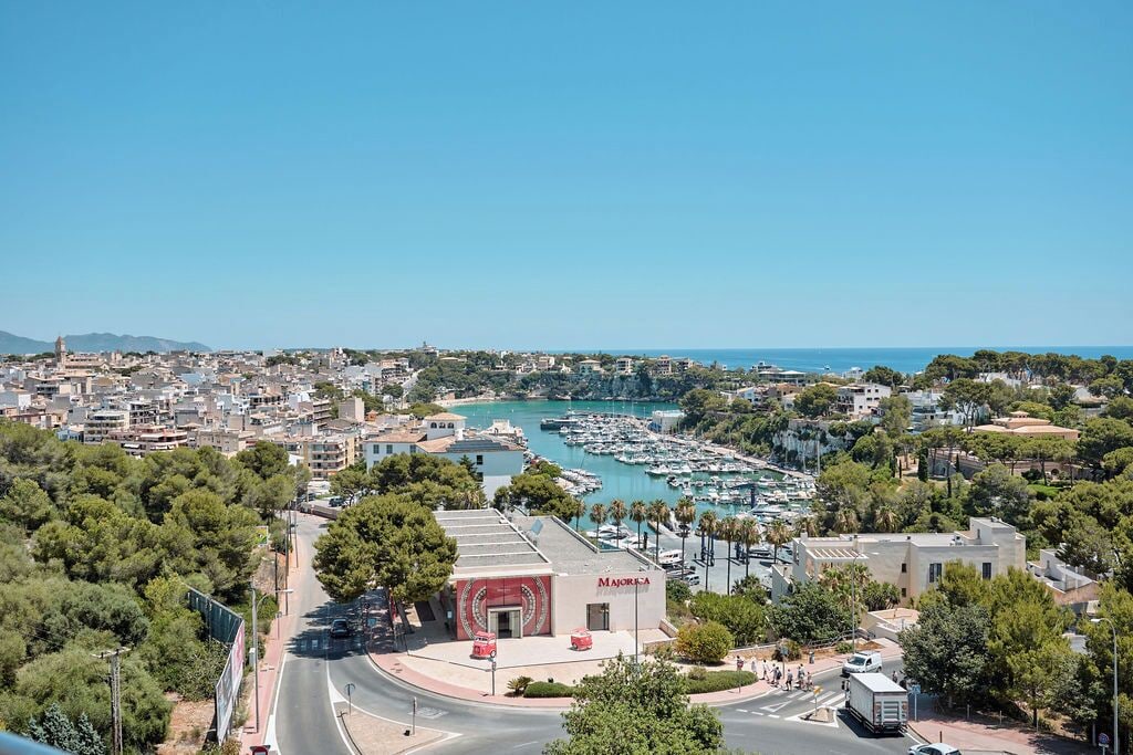 A coastal cityscape with a marina, buildings, and a prominent 'MAJORCA' sign.